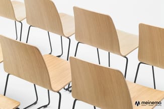 Rij houten stoelen met gebogen rugleuning en zitting, zwart metalen frame, op witte achtergrond.
