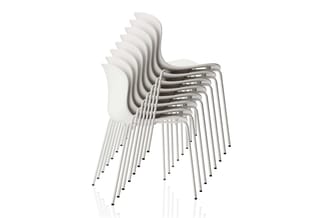 Stapel witte kunststof stoelen met metalen poten, schuin gerangschikt tegen witte achtergrond.