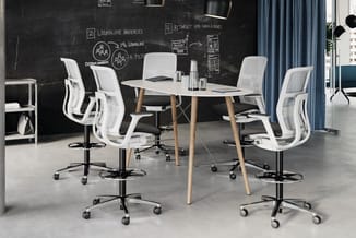 Moderne kantoorruimte met wit rond tafelblad, houten poten, vier witte ergonomische bureaustoelen met zwart zitting, zwart bo