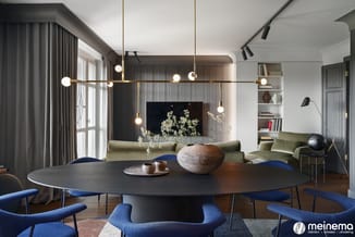 Moderne vergaderruimte met zwarte ronde tafel, blauwe stoelen, groenlinnen bank, hangende goudkleurige design lamp en ingebou