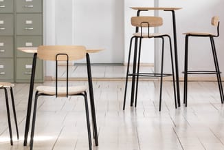 Moderne eetkamer met houten stoelen en barkrukken met zwart stalen frame, rond tafelblad, grijze archiefkast op achtergrond,