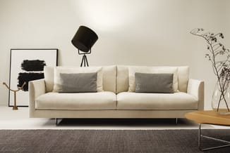 Moderne cremekleurige loungeset met twee zitplaatsen, grijze kussens, metalen poten, in minimalistisch interieur met grijs ta