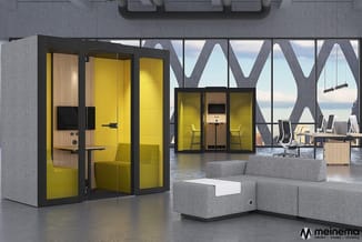 Gele belcel met glazen wanden in modern kantoor met grijze modulaire zithoek, houten accenten en grote raampartijen.
