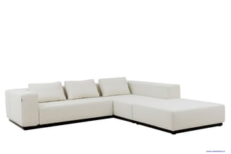 Witte hoekbank met chaise longue, minimalistisch design, zwarte voetlijst, drie losse kussens op de rugleuning.