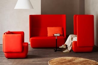 Rode modulaire zitmeubels in een kantoorruimte: fauteuil, bank en scheidingspanelen met hoge rug, met houten vloer en ronde t