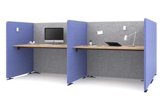 Twee akoestische werkplekken met blauwe en grijze geluidswerende panelen, houten werkbladen en bureauapparatuur.