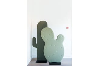 Twee decoratieve cactus-vormige akoestische panelen in groen, geplaatst tegen een witte muur in een kantoorruimte.