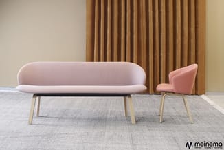 Roze sofa en bijpassende fauteuil met houten poten op grijs tapijt, goudkleurig gordijn op achtergrond.
