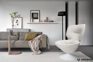 Moderne woonkamer met grijze linnen bank, crèmekleurige eivormige fauteuil, houten bijzettafel, wandkasten en zwarte staande