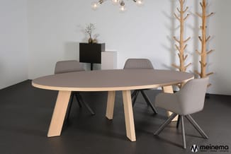 Ronde vergadertafel met grijze tafelblad en houten poten, omringd door grijze stoelen in moderne kantooromgeving met houten a