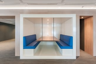 Moderne vergaderruimte met ingebouwde zitbank in blauw en wit, houten tafel, glazen wanden en recessed verlichting in kantoor