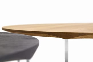 Houten vergadertafel met natuurlijke afwerking en zilveren poot, met grijze bureaustoel ernaast.
