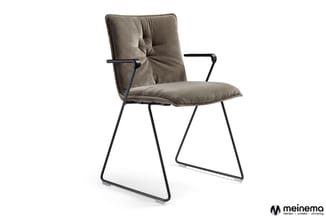 Grijsbeige stoel met gestoffeerde zitting en rugleuning, zwart metalen frame met lage slaapkuip, armsteunen, op witte achterg
