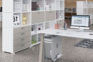 Modern kantoor met witte modulaire kasten, grijze laden, hoekbureau met iMac, Mac Pro tower, roze accessoires en geometrisch