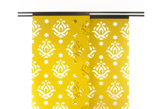 Geel decoratief gordijn met wit en goudkleurig ornamentpatroon en sterren, opgehangen aan zwarte rail.