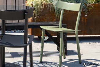 Moderne tuinstoelen: zwarte en lichtgroene kunststof stoelen op terras met betonnen tegels, roestbruine plantenbakken en hout