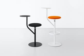 Twee staande barkrukken met voetsteun: links zwart model met gebogen rug, rechts wit model met oranje zitting, beide met rond