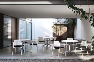 Moderne kantoor-/vergaderruimte met witte kunststof stoelen met zwarte zitting, ronde en rechthoekige tafels, grote glazen de