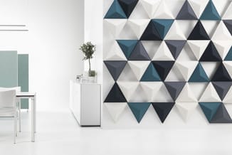 Moderne kantoorruimte met driehoekmuurpanelen in wit, grijs en teal, witte stoel en minimalistisch wit kastje met plant.