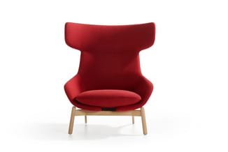 Rode fauteuil met hoge gewelfde rugleuning en zitschaal, houten poten, tegen witte achtergrond.