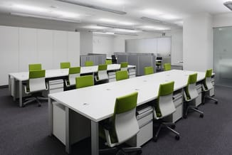 Modern kantoorconcept met witte werkeilanden, groene bureaustoelen, grijze kasten en LED-verlichting in open ruimte.
