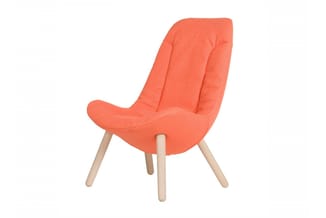 Moderne fauteuil met koraalrode bekleding, gebogen rugleuning en natuurlijke houten poten.