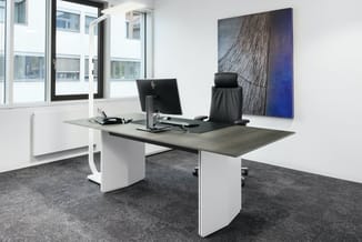 Modern kantoor met grijze werkplek, wit onderstel, zwarte bureaustoel, HP-monitor, donkergrijs tapijt en abstract kunstwerk a