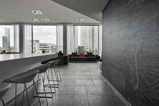 Modern kantoor met witte bar met zwarte barkrukken, grijze tegelvloer, zwarte wandbekleding, loungebank en grote ramen met ui