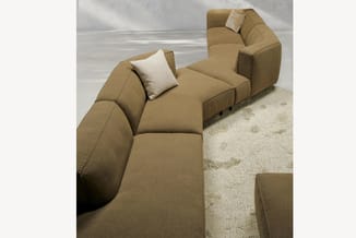 Bruinbeige modulaire bank met afzonderlijke zitblokken, crèmekleurige kussens en lichte vloerkleed in minimalistisch interieu