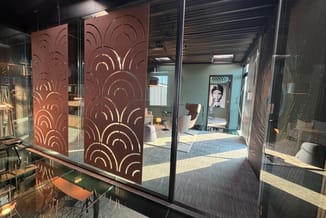 Bruine decoratieve scheidingswanden met halfronde patronen voor kantoorruimte, glaswanden en grijze vloerbekleding zichtbaar.
