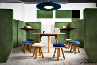 Groene akoestische werkplek met houten tafel, houten krukken met blauwe en witte zittingen, wandplanken, blauwe hanglamp en w