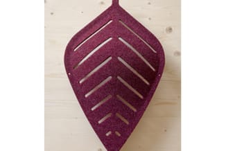 Paars vilt akoestisch paneel in bladform met uitgesneden pijlmotieven, hangend aan houten wand.
