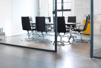 Moderne vergaderruimte met glazen wand, zwarte bureaustoelen met chromen onderstel, houten tafel en grote ramen met uitzicht.