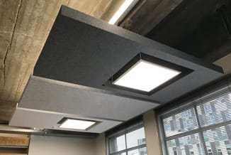 Akoestisch plafond met ingebouwde LED-verlichting in kantoorruimte met betonnen bovenkant en aluminium jaloeziëen.