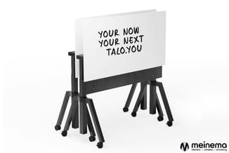 Mobiel whiteboard op zwart onderstel met wielen. Witte schrijfplaat met handgeschreven tekst "YOUR NOW YOUR NEXT TALO.YOU".