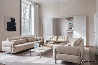 Moderne woonkamer met twee beige stoffen fauteuils, beige sofa en twee crèmekleurige design stoelen rond witte salontafel op