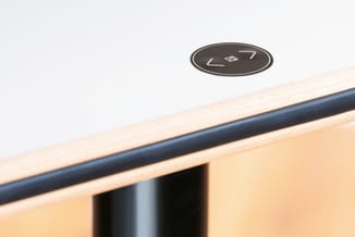 Houten bureau met zwart metalen frame en geïntegreerde ronde schakelaar met nummer 7 op de rand.