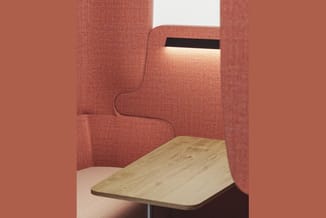 Houten tafel in een akoestische ruimte met roze/terracotta stof bekleding en witte plafondpanelen.
