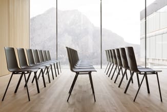 Moderne stoelen met zwarte metalen poten en donkergrijze bekleding in rijen opgesteld in minimalistische ruimte met grote ram