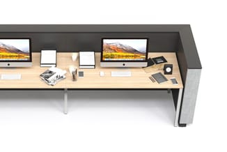 Twee werkplekken met houten blad, twee iMac-monitoren, witte toetsenborden, grijze akoestische wanden, bureaustoelen en kanto