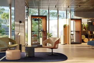 Modern kantoor met oranje akoestische boxen, beige stoelen, zwart rond tapijt, houten vloer, grote ramen en groene planten.