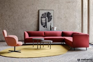 Rode hoekbank met gele ronde vloerkleed, roze fauteuil, twee bijzettafels en abstract kunstwerk in minimalistisch interieur.