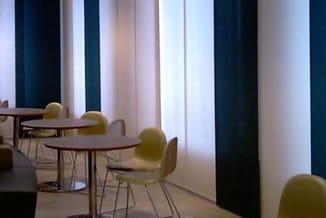 Moderne kantoorruimte met ronde tafels, gele/olijfgroene stoelen, verticale gordijnen in donkerblauw en wit, minimalistisch i