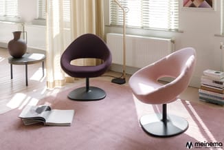 Moderne lounge met twee draaibare fauteuils in donkerpaars en lichtroze, zwarte voetstukken, roze tapijt, houten vloer, natuu