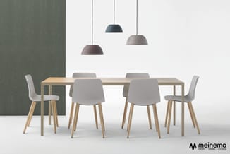 Houten vergadertafel met grijze stoelen en drie hangende koepellamp-pendelarmaturen in zwart, donkergrijs en lichtgrijs boven