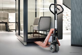 Rode heftruk in moderne kantoorruimte met glazen wanden, grijze stoel en minimalistisch ingericht interieur.