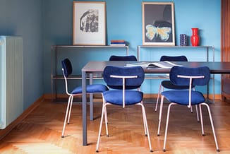 Moderne vergaderruimte met grijze tafel, blauwe stoelen met wit frame, houten vloer, blauwe wanden en metalen wandkasten met