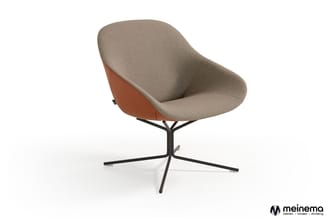 Moderne fauteuil met beige stoffering en cognackleurig leren achterpaneel, op zwart metalen spinnenpootonderstel.