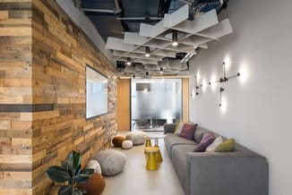 Modern kantoorinterieur met houten wand, grijze loungebank met gekleurde kussens, poefjes, gele bijzettafel en design plafond