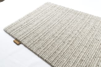 Beige geweven tapijt met ribtextuur en houten details, zicht vanaf bovenkant op witte achtergrond.